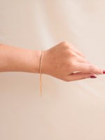 Hand wearing a thin bracelet on a plain background