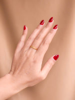 Hand with red nail polish on a beige background