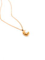 Gold necklace with a heart-shaped pendant on a white background