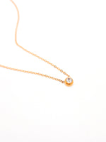 Gold necklace with a small round pendant on a white background