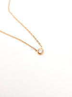 Gold necklace with a small diamond pendant on a white background