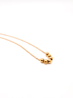 Gold necklace with three beads on a white background