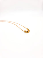 Gold necklace with three beads on a white background