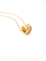 Gold necklace with a decorative pendant on a white background