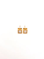 Gold square earrings with clear gemstones on a white background