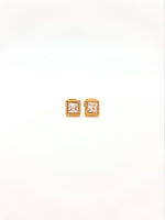 Pair of square stud earrings with rose gold frame and clear gemstones on a white background