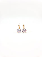 Pair of gold earrings with clear gemstones on a white background