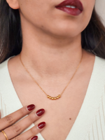Close-up of a person wearing a gold necklace with a white top.
