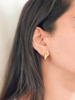 Gold hoop earrings with zircon stones worn by a person with dark hair.