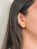 Gold earring worn by a person with a neutral background