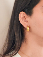 Gold hoop earring worn by a person with a neutral background