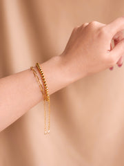 Gold bracelet on a wrist against a beige background