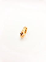 Gold ring with a textured band on a white background