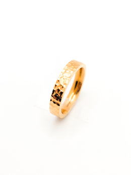 Gold ring with a textured design on a white background