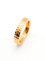 Gold ring with a textured design on a white background