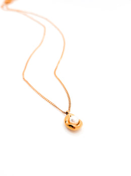 Gold necklace with a heart-shaped pendant on a white background