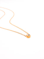 Gold necklace with a small round pendant on a white background