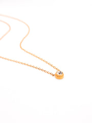 Gold necklace with a small round pendant on a white background