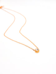 Gold necklace with a small round pendant on a white background