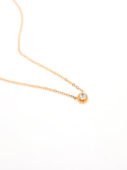 Gold necklace with a small round pendant on a white background