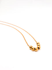 Gold necklace with three beads on a white background