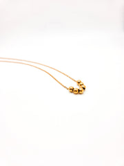 Gold necklace with three beads on a white background