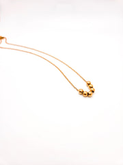 Gold necklace with three beads on a white background
