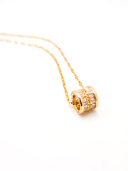 Gold necklace with a cylindrical pendant on a white background