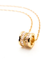 Gold necklace with a cylindrical pendant on a white background