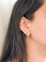 Gold hoop earrings with zircon stones worn by a person with dark hair.