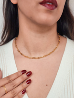 Close-up of a person wearing a gold chain necklace with a neutral background