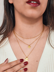 Close-up of a person wearing a gold necklace with circular pendants.