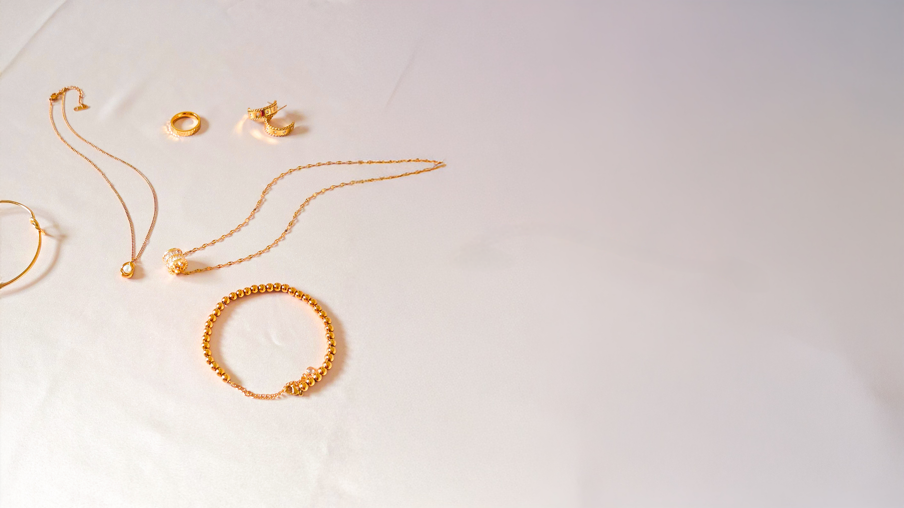 Gold jewelry including bracelets and necklaces on a white surface